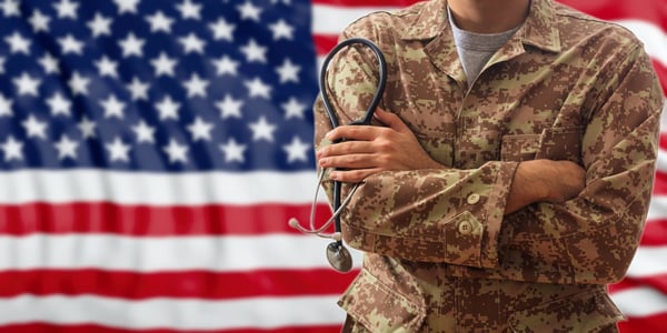Soldier holding a stethoscope in front of an American flag.