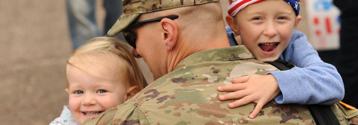 Male soldier holding his two children.